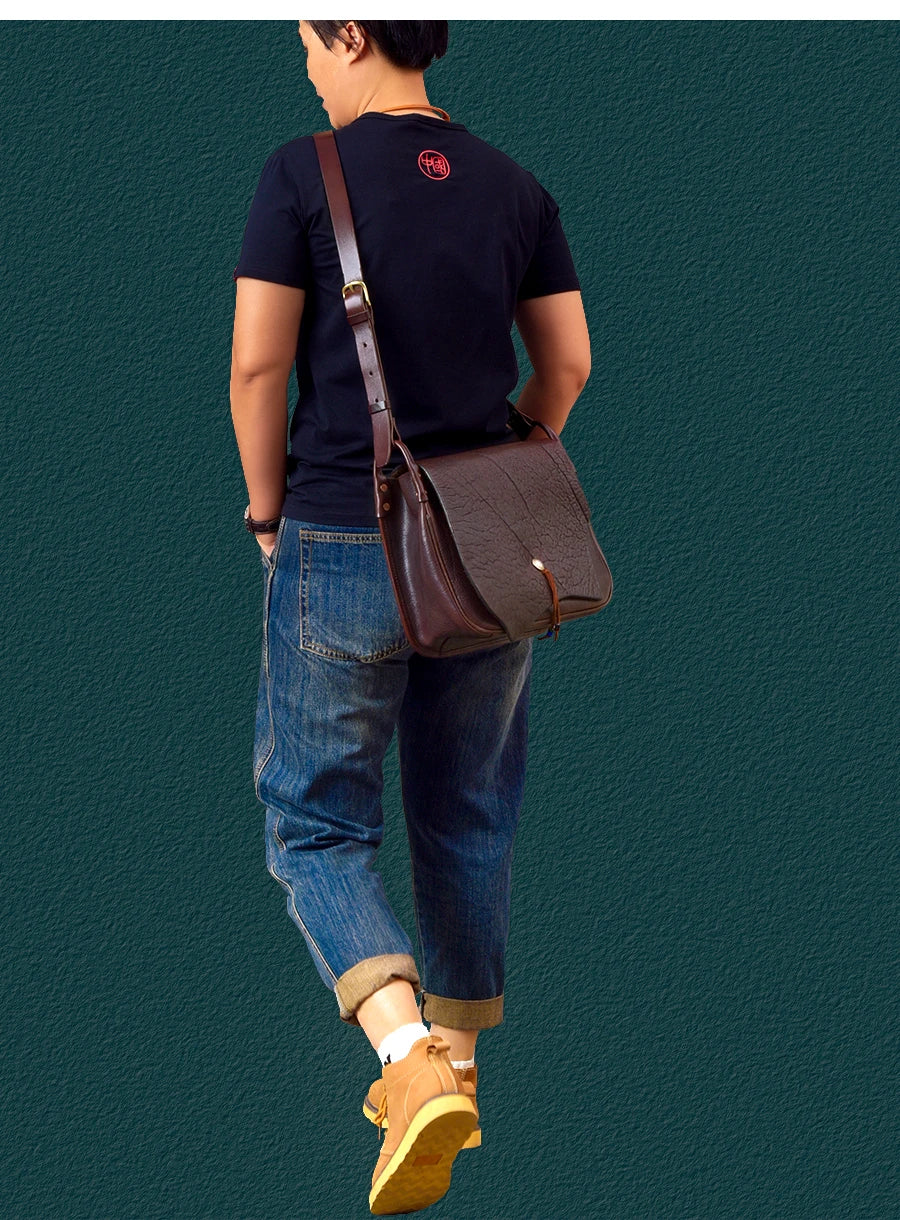 Vintage handmade dark brown cowhide leather messenger bag with adjustable shoulder strap and textured flap closure.