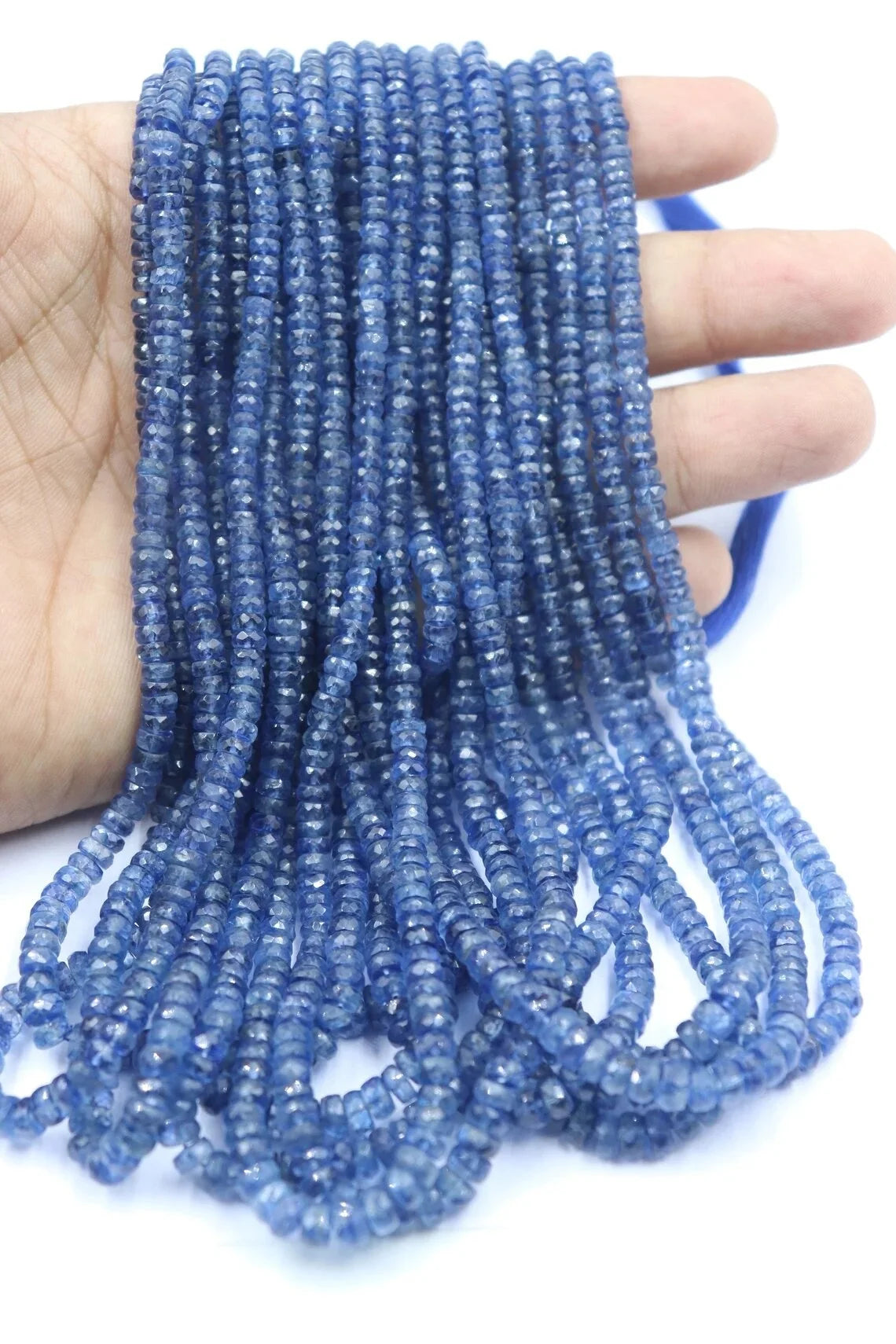 Kyanite rondelle bead strand in hand, faceted blue beads with small drilled holes