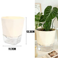 Self-watering beige plant pot with clear reservoir base holding leafy plants