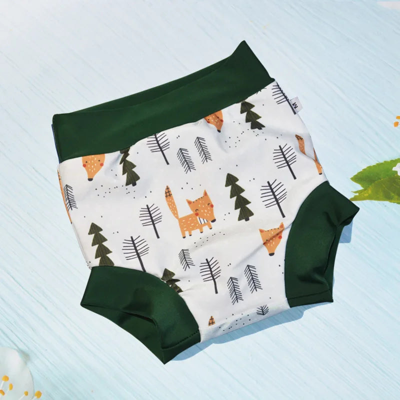 Medium-sized baby cloth diaper with forest fox and tree print, dark green trim, and high-waisted design.