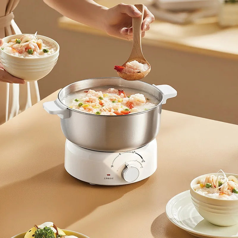 Portable electric hot pot with stainless bowl on white base, spoon lifting food