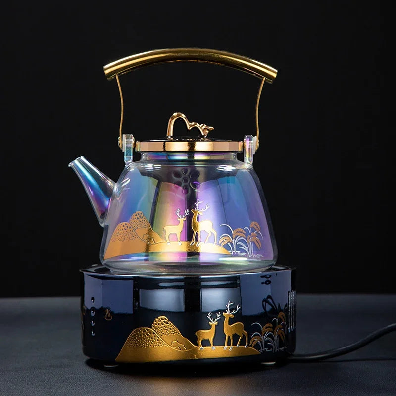 Iridescent glass tea kettle with gold deer design and handle on a matching black electric induction stove base.