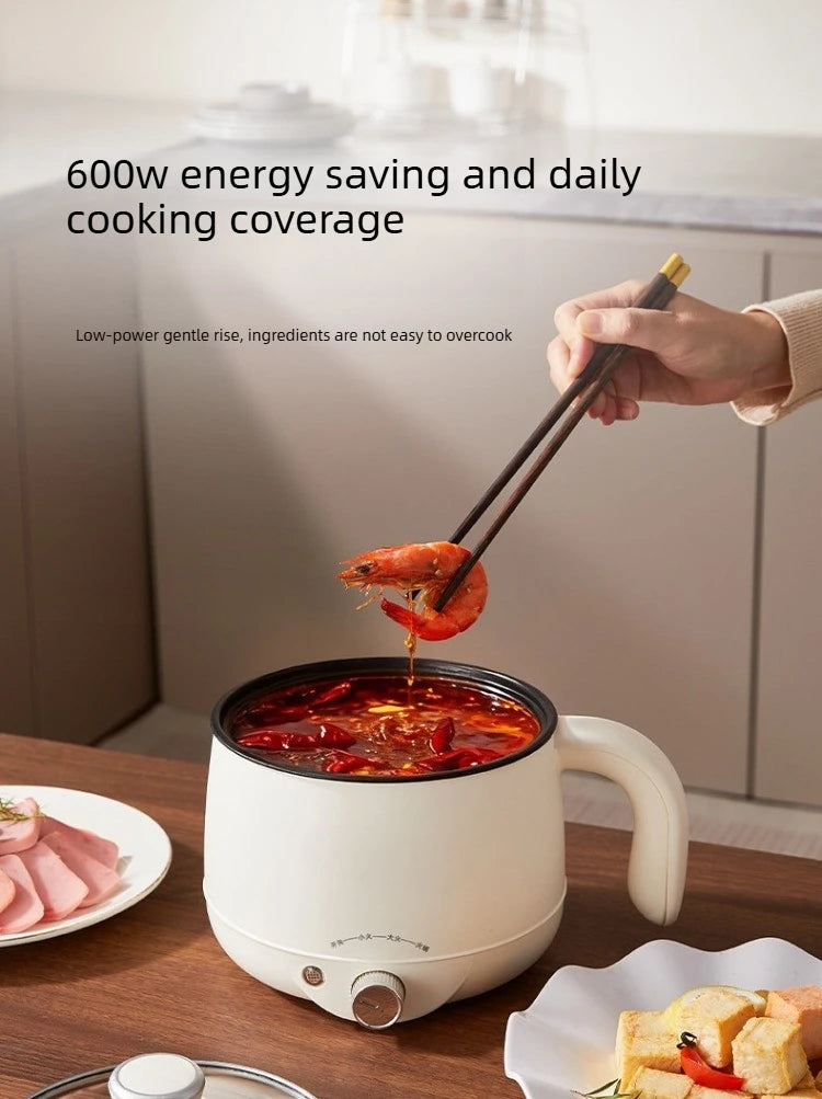 White electric hot pot with dark inner, simmering red soup; front control knob visible