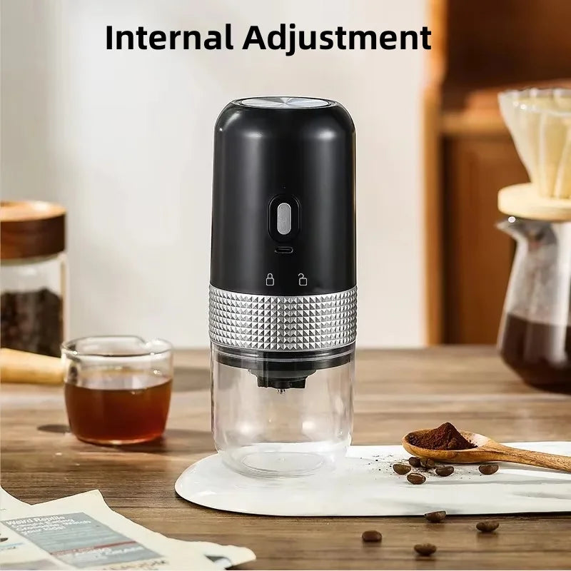 Portable black electric coffee grinder with metallic textured grip, transparent bean container, and USB charging port.