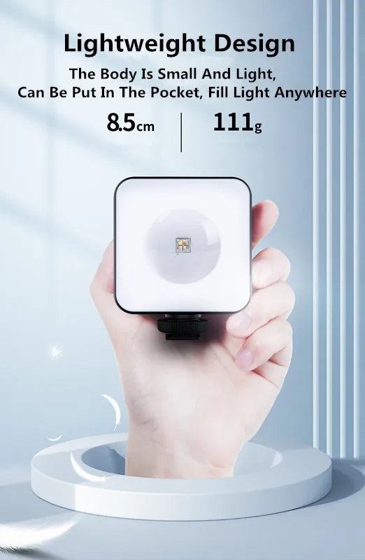 Square 8.5cm portable LED fill light held in hand, featuring a white diffuser and mounting base for photography.
