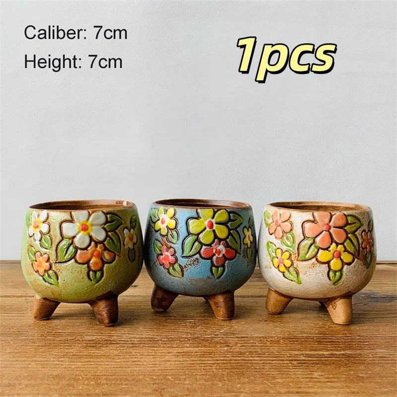 Three small ceramic plant pots with painted flowers and short three-legged bases