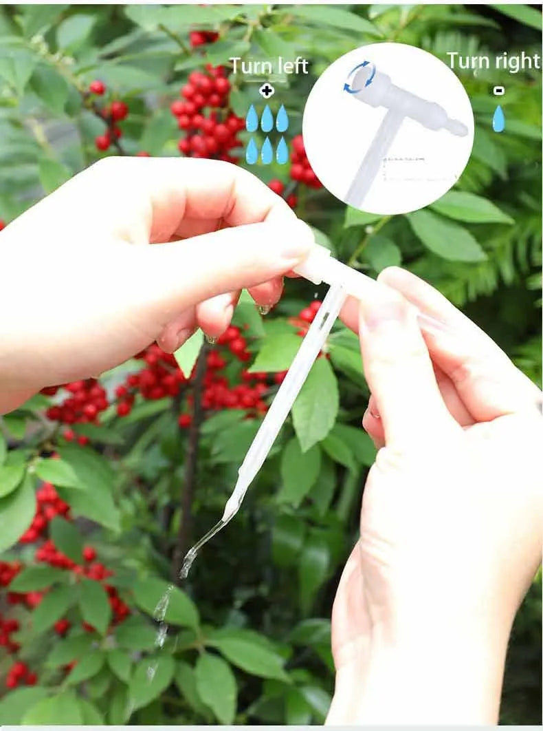 Adjustable white drip tube nozzle held by hands over a red flowering plant