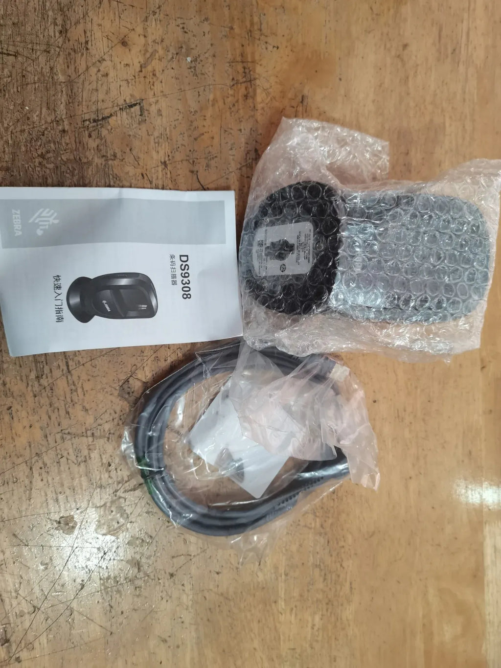 Zebra DS9308 barcode scanner package with bubble wrap, manual, and cable set