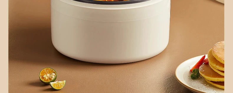 White electric cooking pot on countertop with black rim and visible food inside
