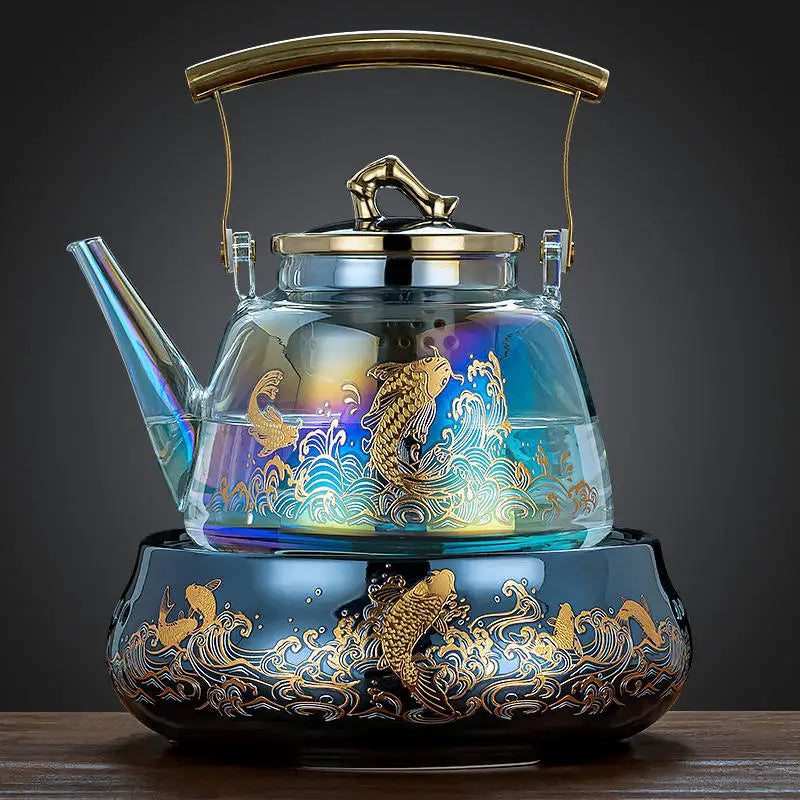 Iridescent glass tea kettle with gold koi fish design, brass handle, and matching ornate ceramic base stove.
