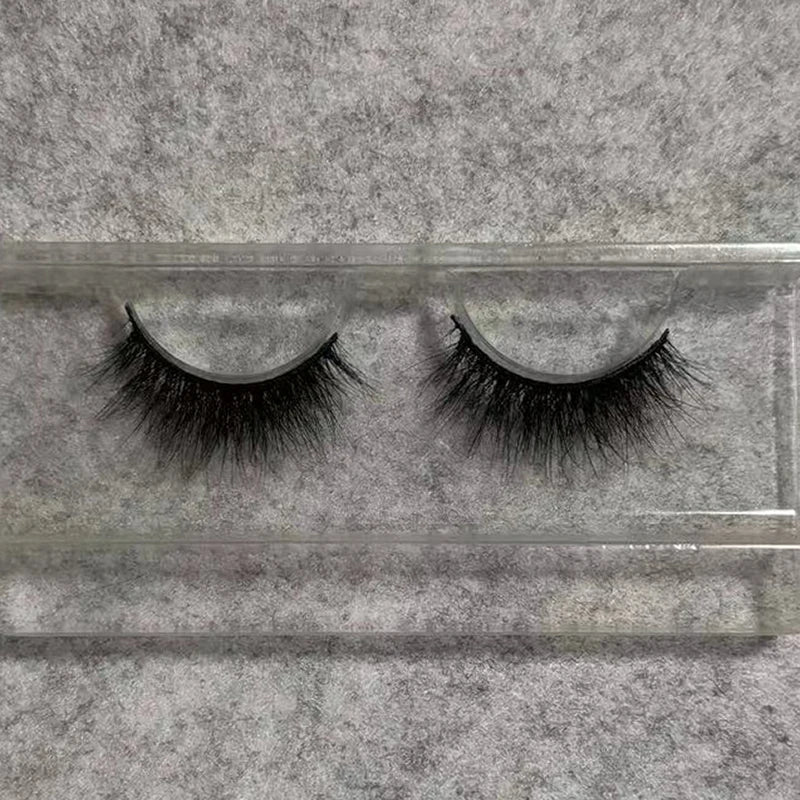 Pair of black 3D mink false eyelashes with a soft, flexible band, displayed in a clear plastic storage tray.