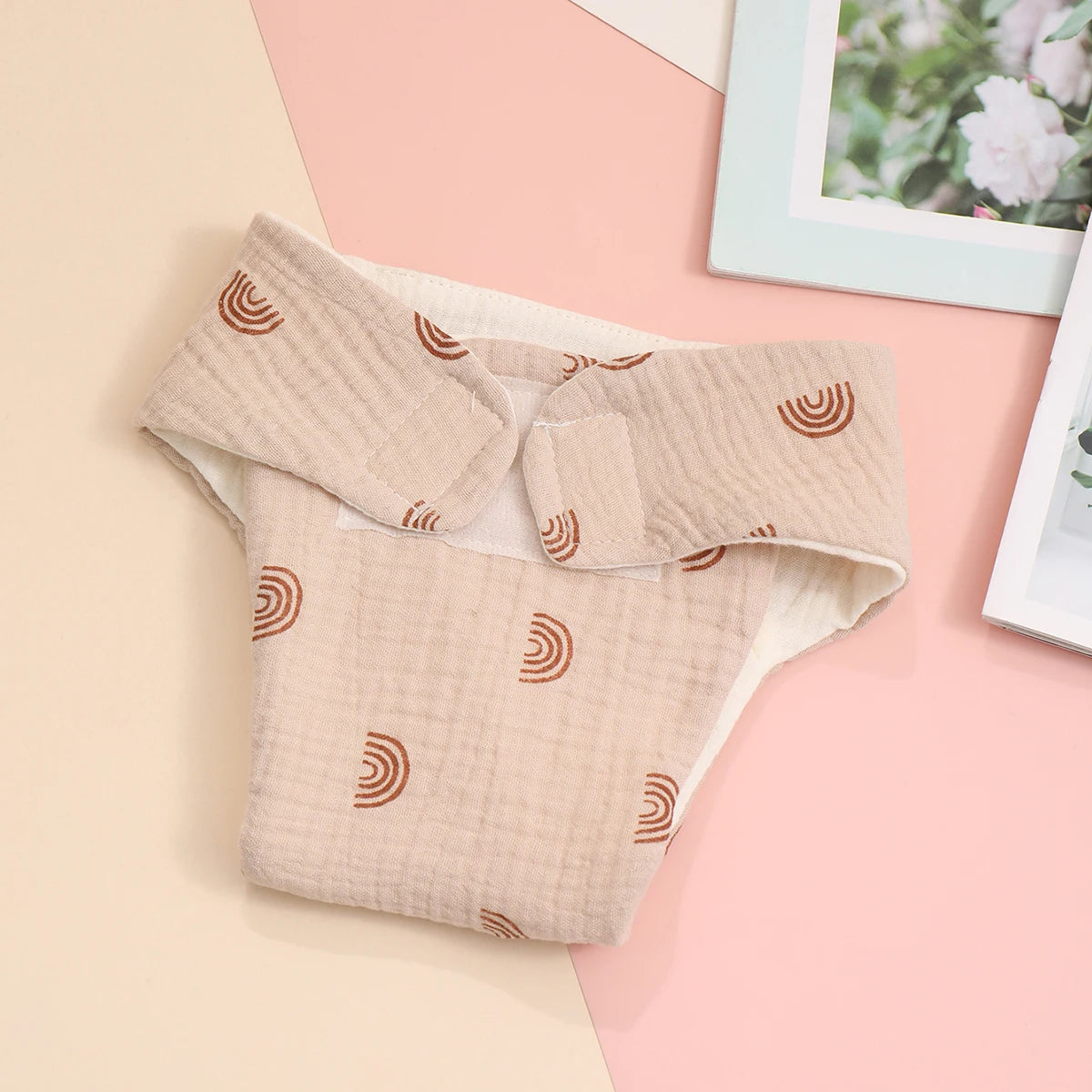 Beige muslin cloth baby diaper with brown rainbow print and adjustable velcro closure for gentle baby care.