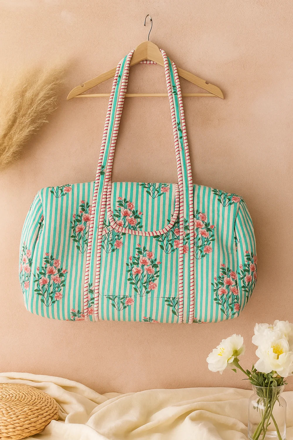 Artisan quilted weekender duffle bag in light green stripes and pink floral print with red trim details.