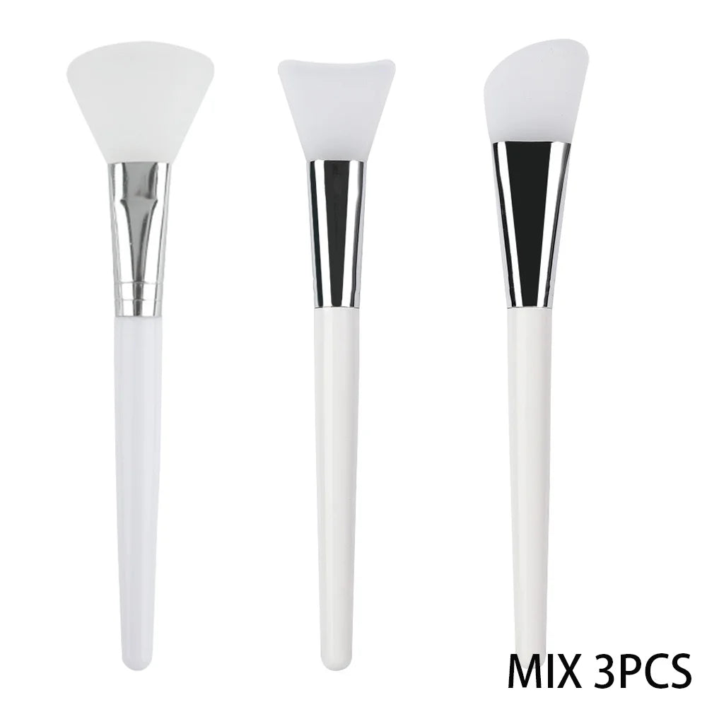 Three silicone face mask brushes with white handles, silver ferrules, and varied silicone head shapes.