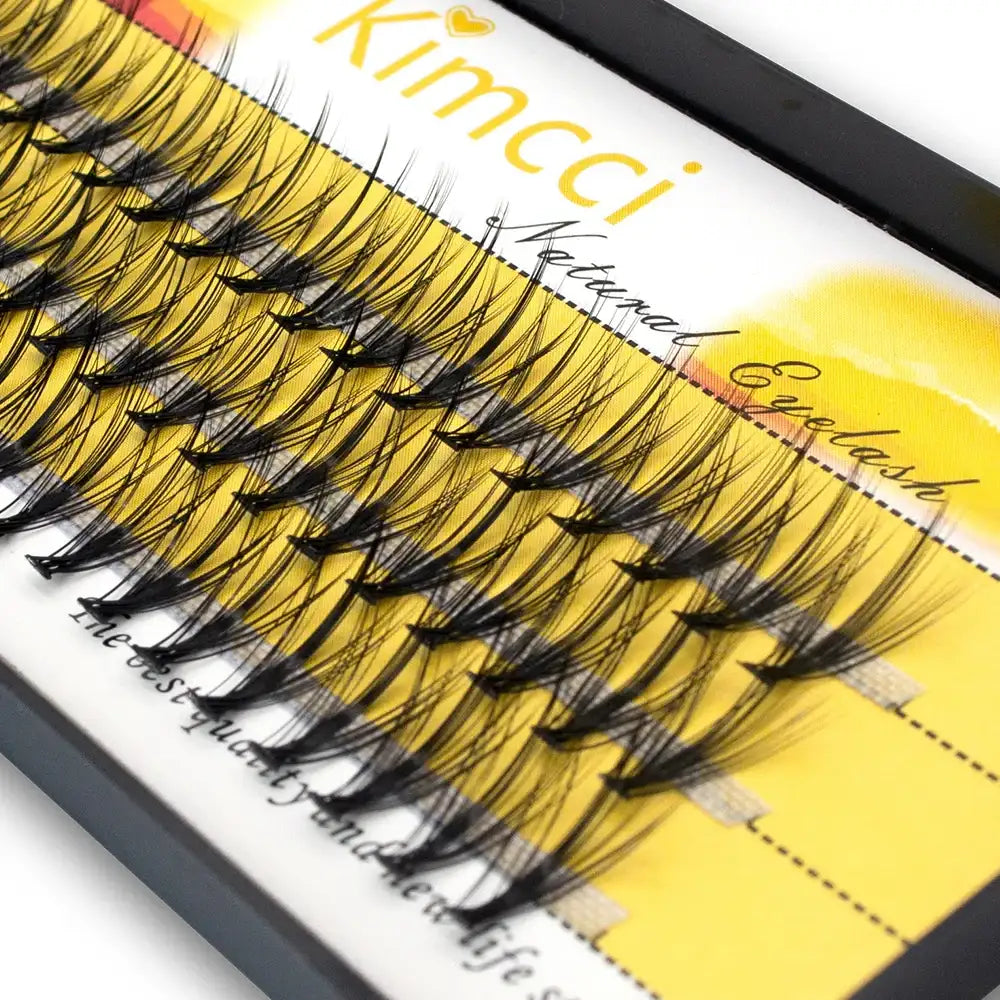 Tray of black individual mink eyelash clusters with a wispy 3D volume style, arranged in rows on a yellow card.
