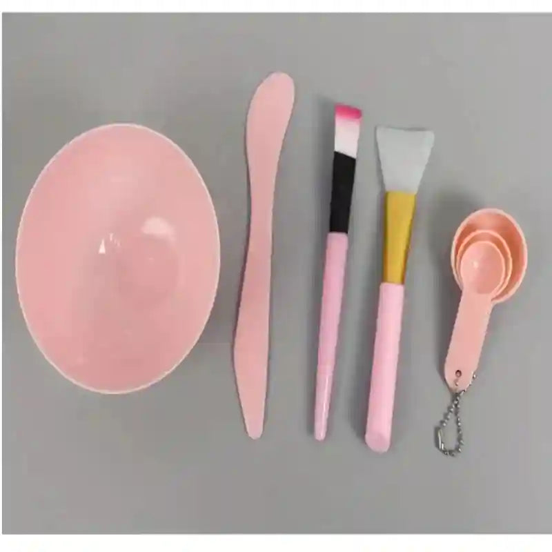 A 7-piece pink face mask mixing set, including a bowl, spatula, two brushes, and three measuring spoons on a chain.