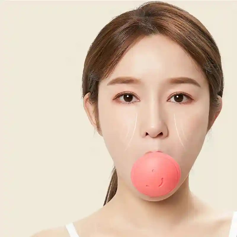 A woman demonstrates a round, pink silicone facial exercise tool held in her mouth to tone and lift her face.