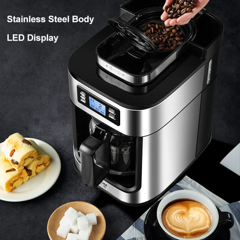 Modern stainless steel drip coffee maker with integrated bean grinder, LED display, and glass carafe on dark table.