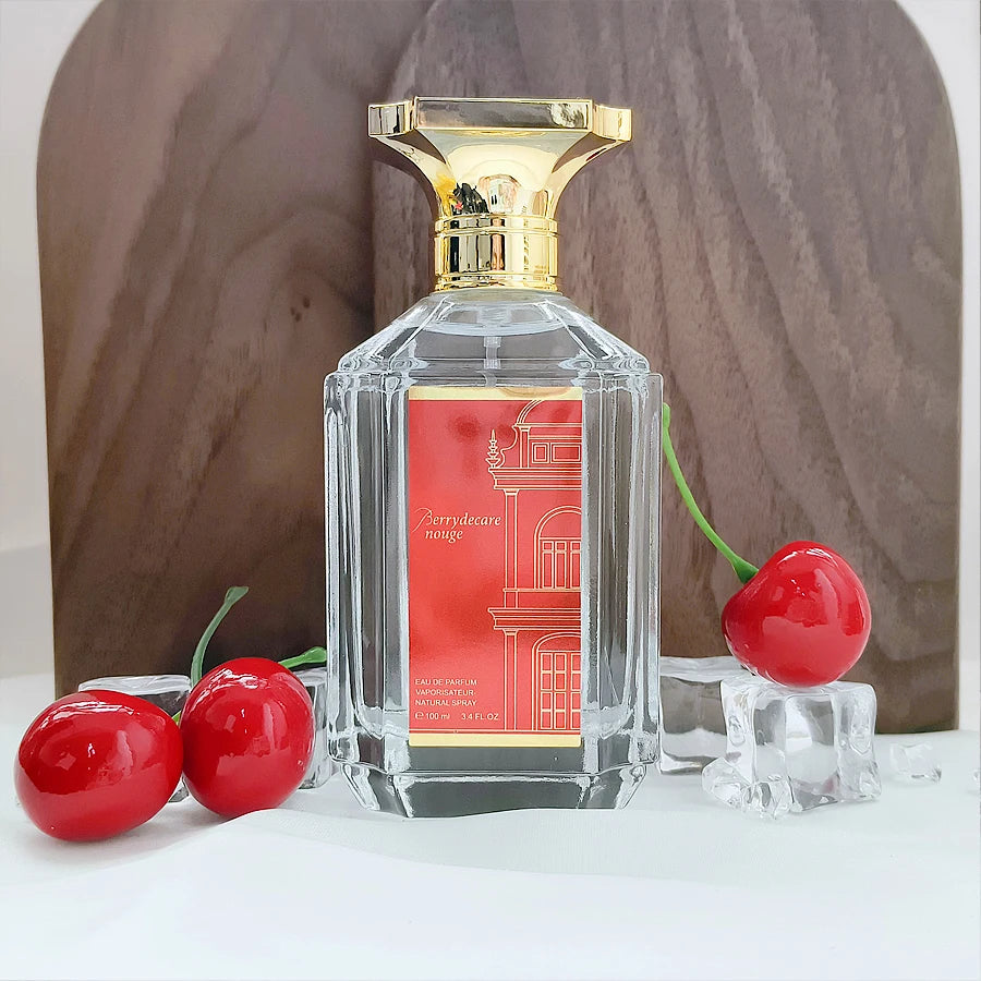 Berrydecare Rouge eau de parfum in a rectangular glass bottle with a gold cap, surrounded by cherries and ice cubes.