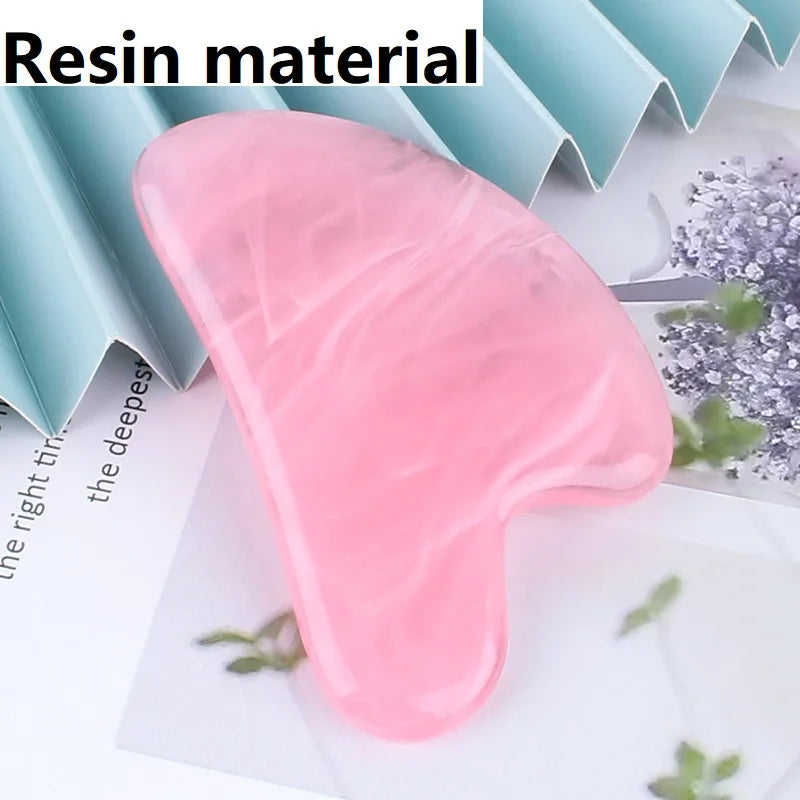 Pink heart-shaped resin gua sha massage tool with a smooth, marbled texture resting on a paper background.