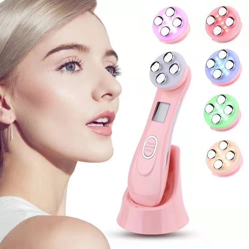 Pink handheld LED facial massager with four metal nodes on a charging base, showing various colored light settings.