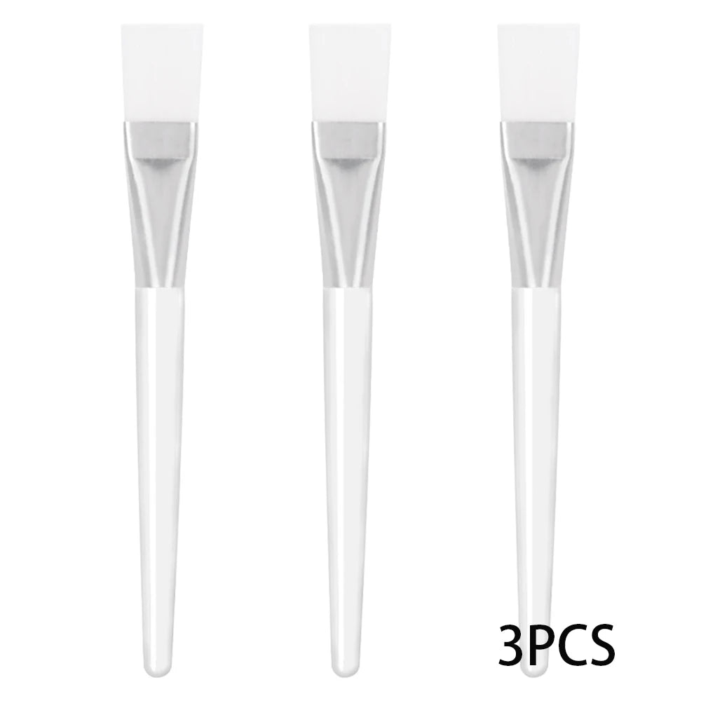 Three facial mask brushes with flexible white silicone tips, silver ferrules, and translucent white plastic handles.