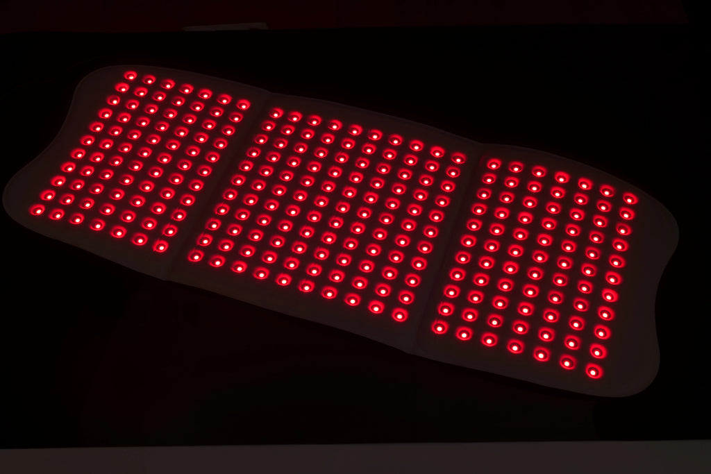 A large, three-panel rectangular red light therapy mat featuring a dense grid of glowing red LED lights.