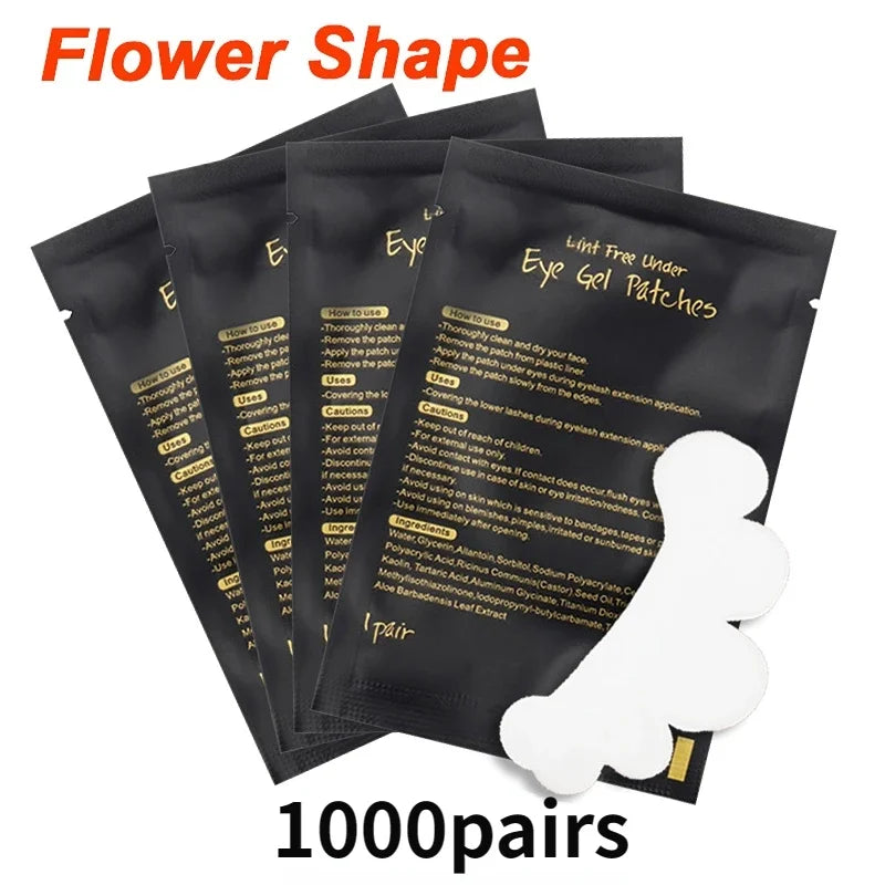 White flower-shaped lint-free gel eye patches for lash extensions on black individual foil packaging sachets.