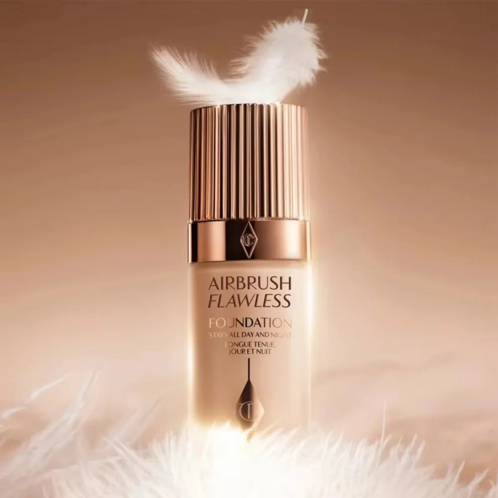 Charlotte Tilbury Airbrush Flawless Foundation bottle in a nude shade with a rose gold cap and white feathers.