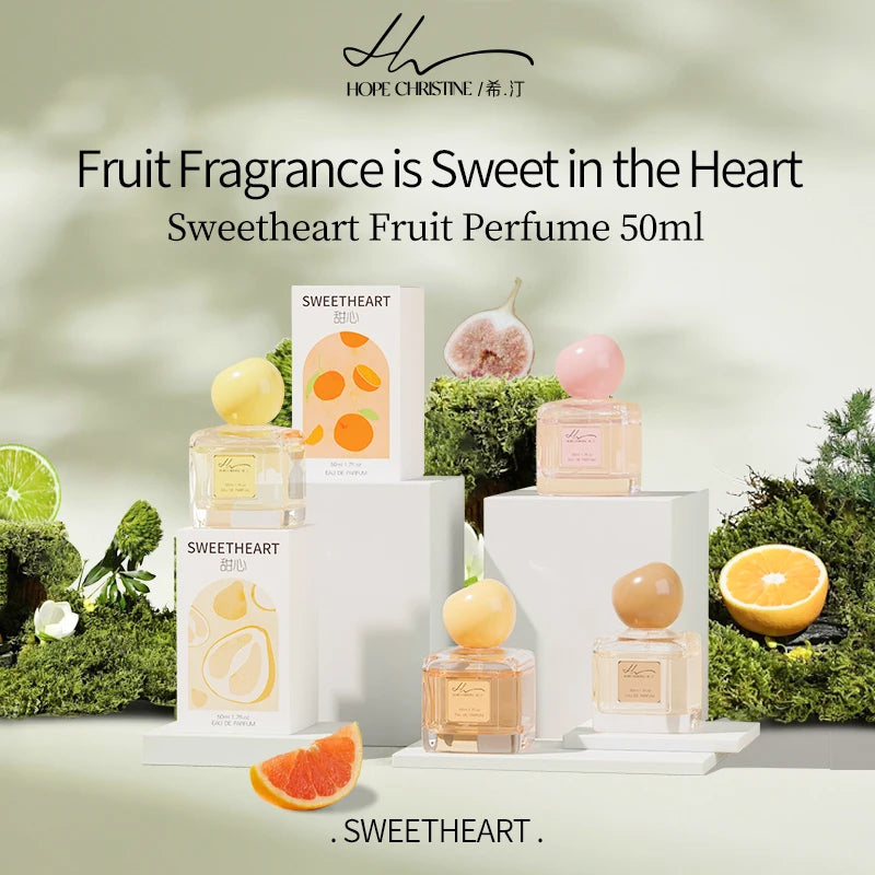 Sweetheart Fruit Perfume 50ml bottles with round caps on white pedestals, surrounded by moss and fresh fruit slices.