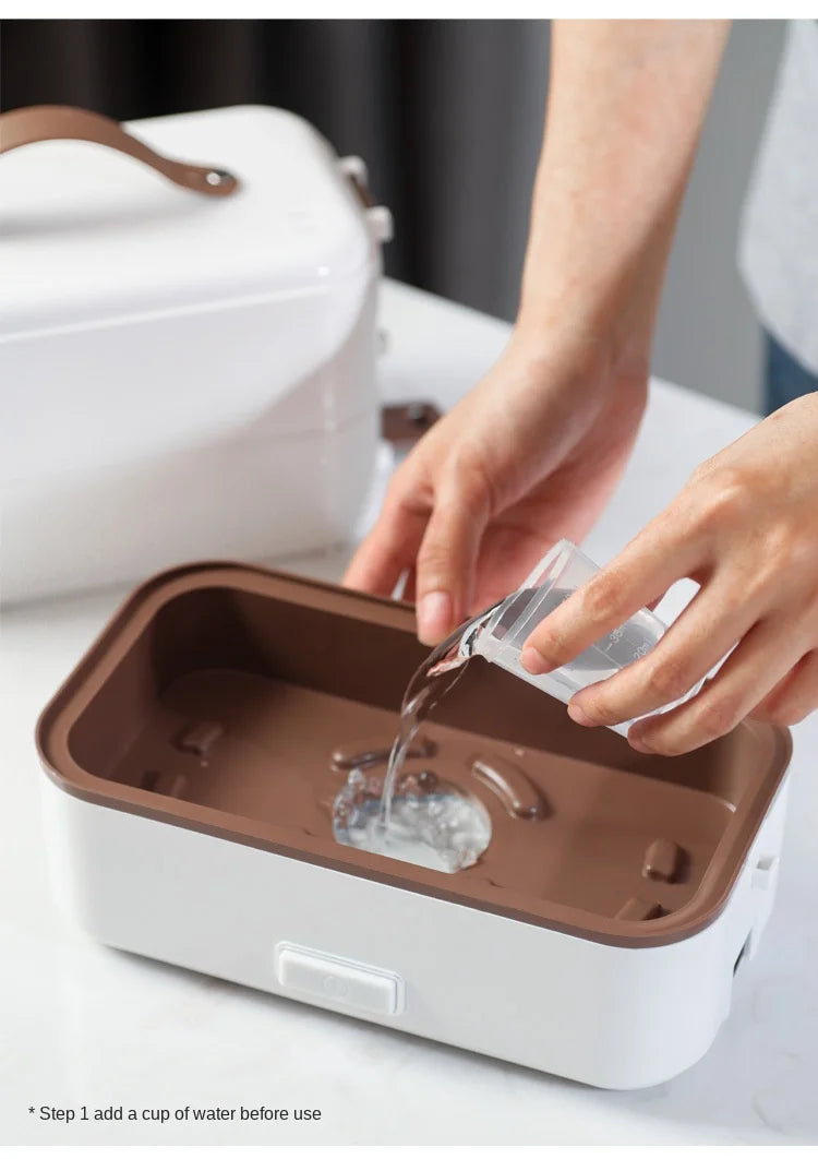 Close-up of hand pouring water into inner base of electric heating lunch box