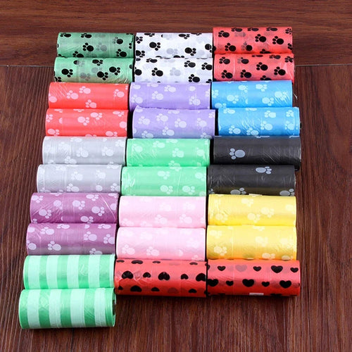 Dog waste bag rolls with paw prints in mixed colors, neatly arranged on a wooden floor