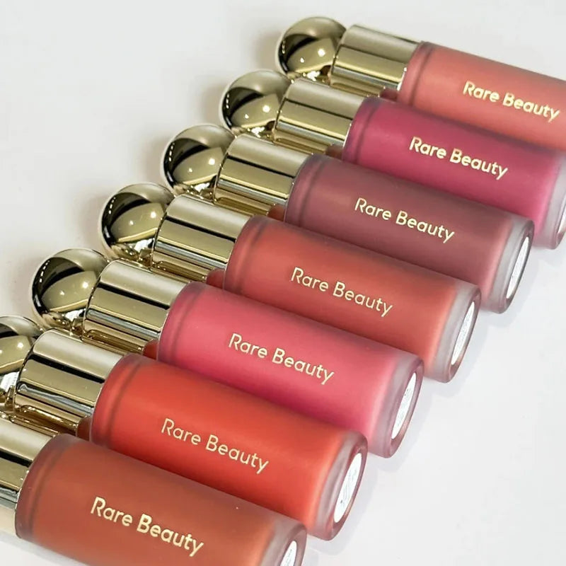 Rare Beauty Soft Pinch liquid blush collection in assorted matte shades with gold caps arranged on a white background.