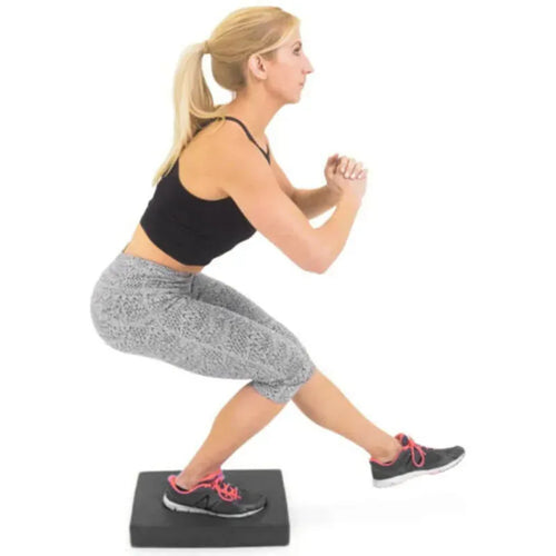 Soft balance pad foam exercise cushion for smart yoga mats, side view of woman doing single-leg squat fitness training.