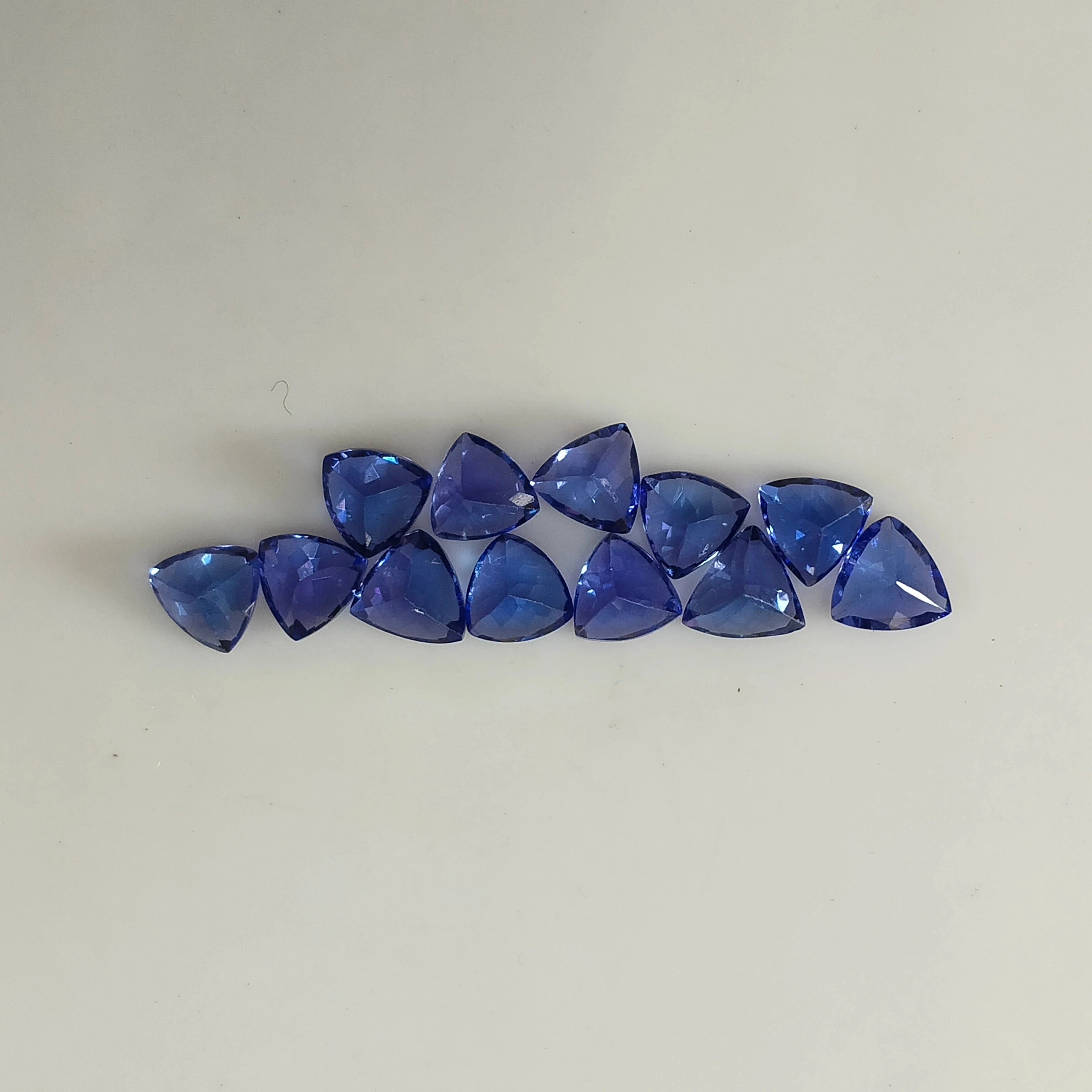 Row of loose blue trillion-cut gemstones with triangular facets