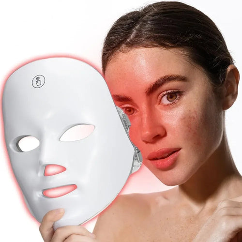 Woman holding a white oval red light therapy LED face mask device for skin rejuvenation and wellness.
