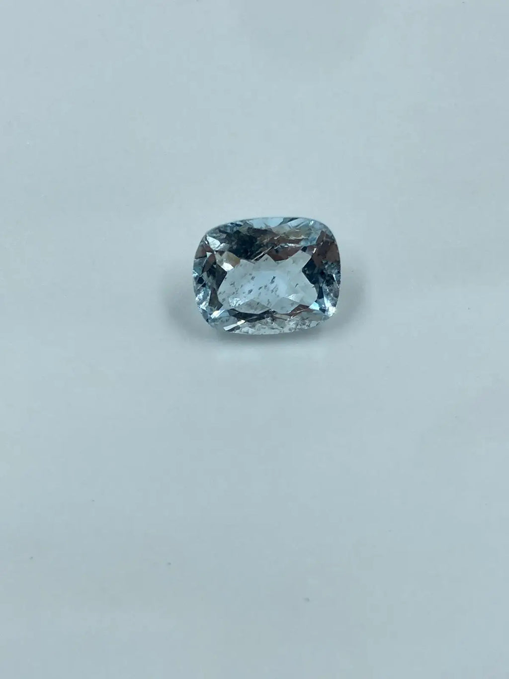 Cushion-cut aquamarine gemstone, sky blue, loose stone on light background