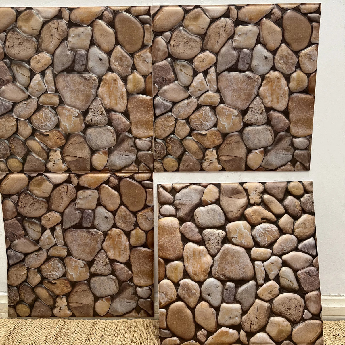 Pebble-stone peel-and-stick tile backsplash squares in tan and brown, textured look