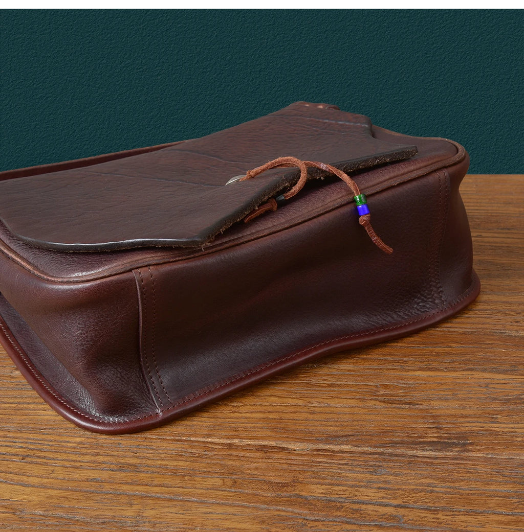 Vintage brown handmade cowhide leather messenger bag with flap closure, tie detail, and unique artisan aesthetic.