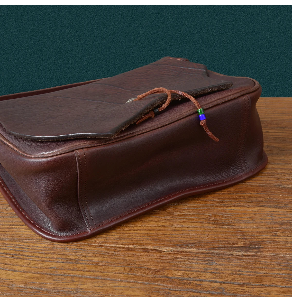 Vintage brown handmade cowhide leather messenger bag with flap closure, tie detail, and unique artisan aesthetic.