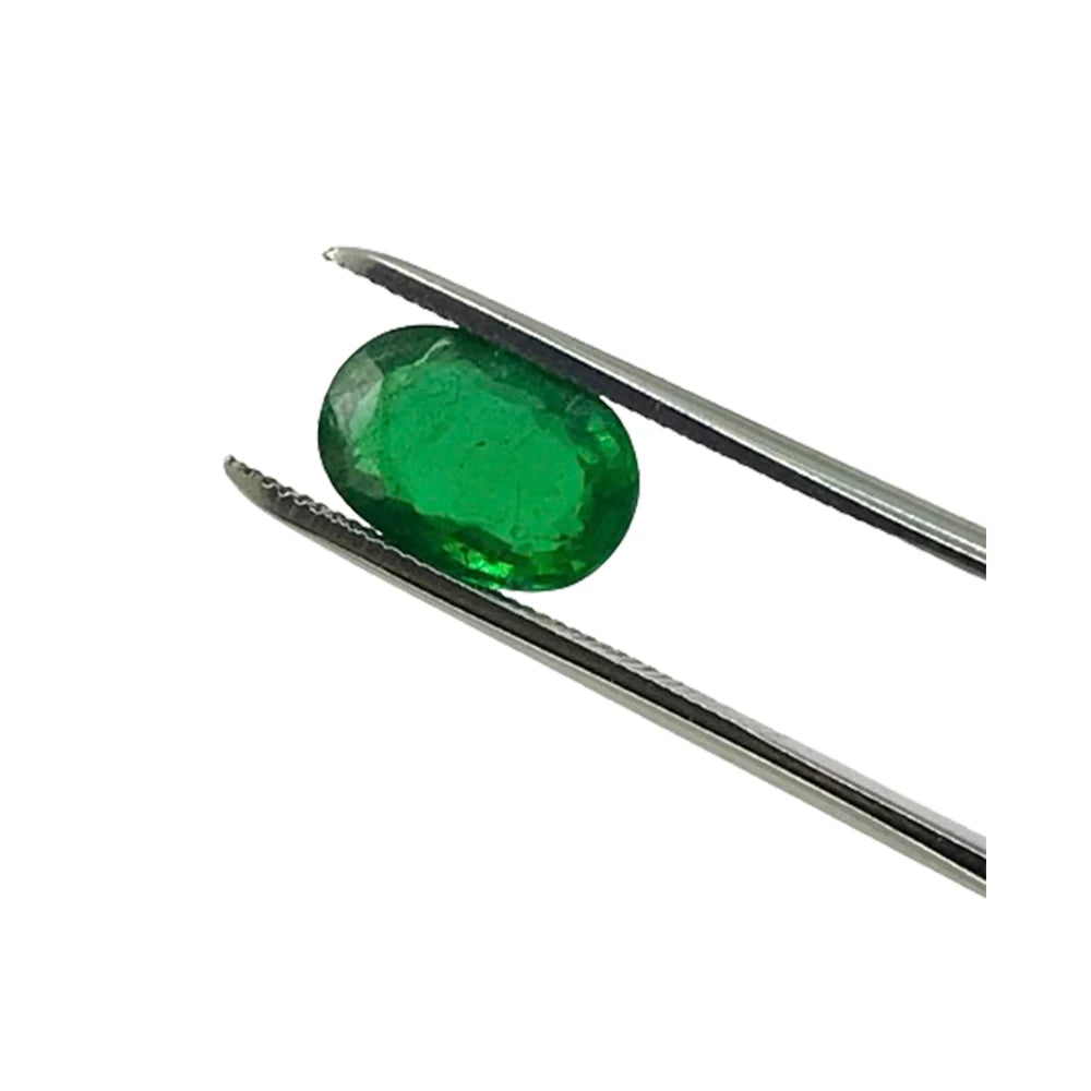 Green oval loose gemstone held by metal tweezers, faceted for jewelry making