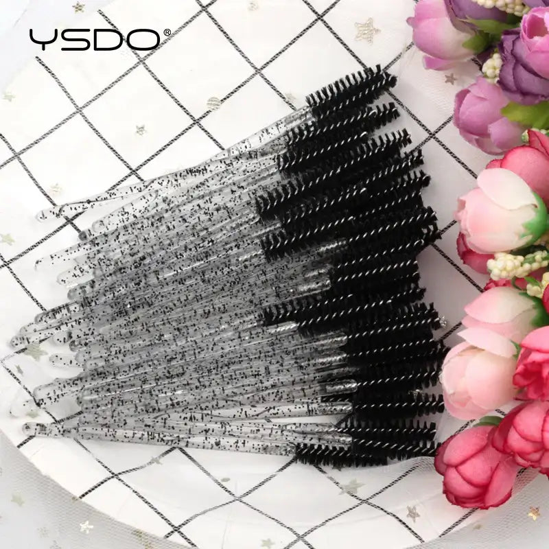 Disposable mascara brushes with black bristles and clear, glitter-infused plastic handles.