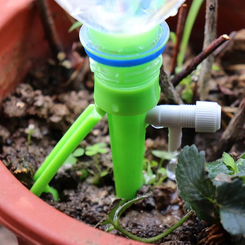 Close-up of green and gray auto drip irrigation spike watering into garden soil