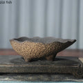 Textured ceramic flowerpot planter with dark interior, bowl shape, and rough speckled finish