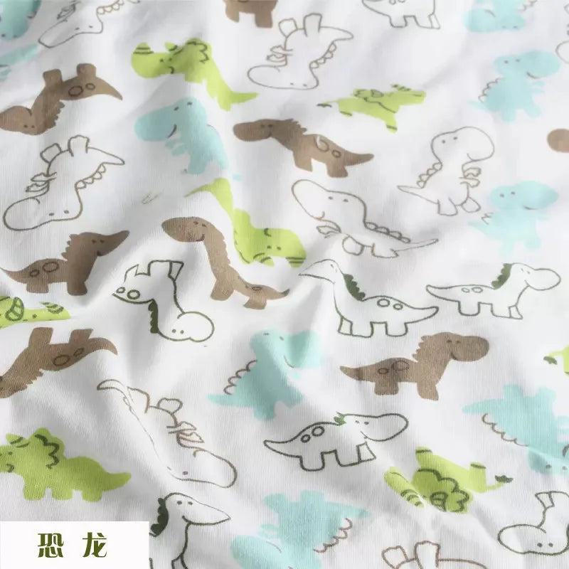Soft white knit jersey fabric featuring a playful pattern of light green, blue, and brown cartoon dinosaurs.
