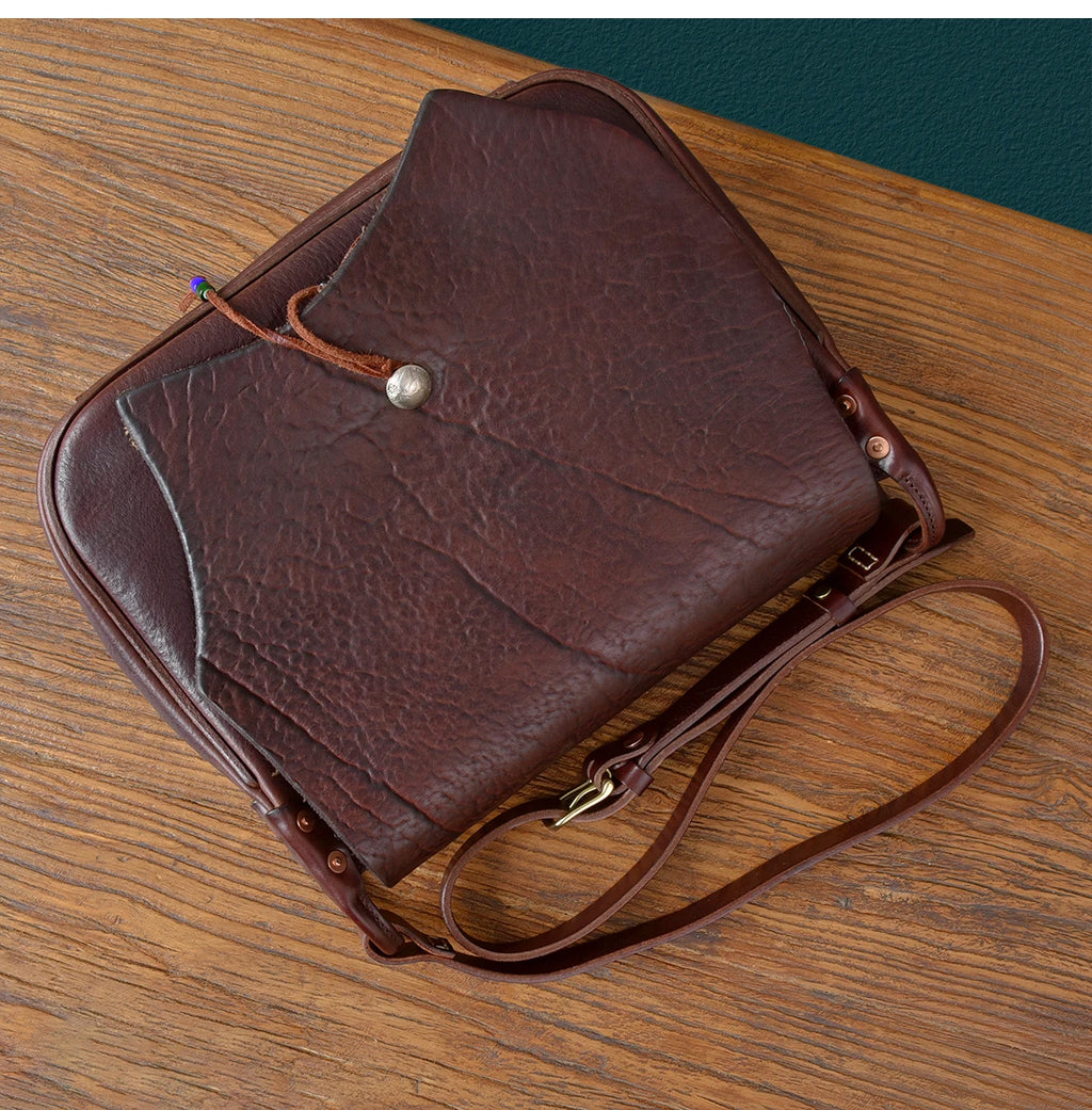 Vintage dark brown genuine cowhide leather messenger bag with a button closure and adjustable shoulder strap.