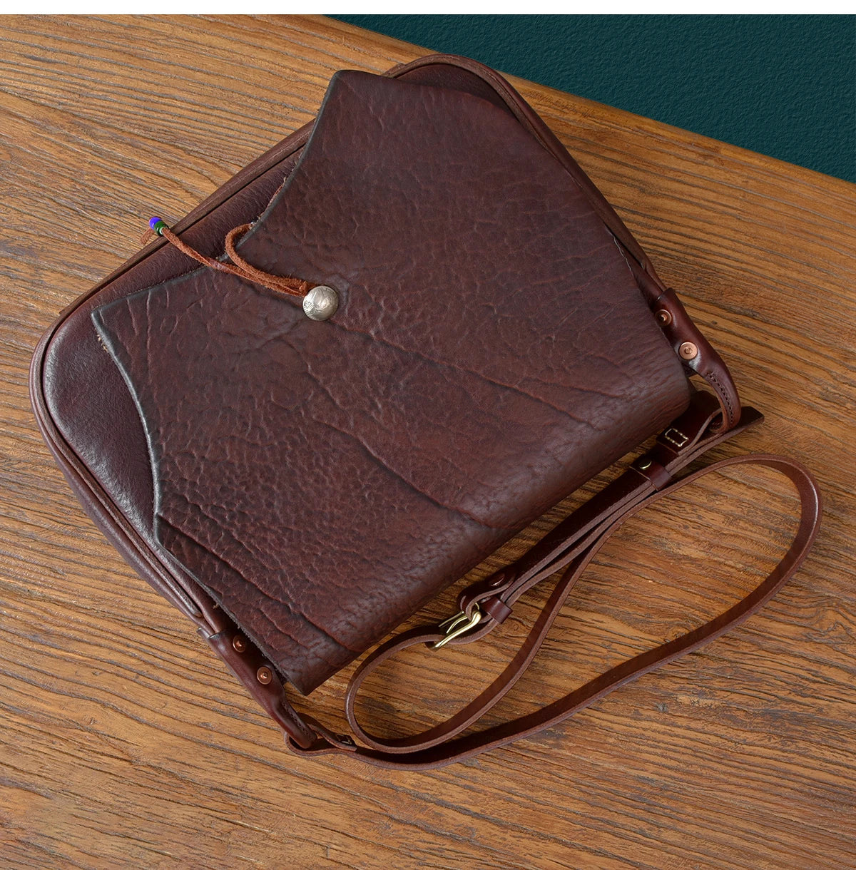 Vintage dark brown genuine cowhide leather messenger bag with a button closure and adjustable shoulder strap.