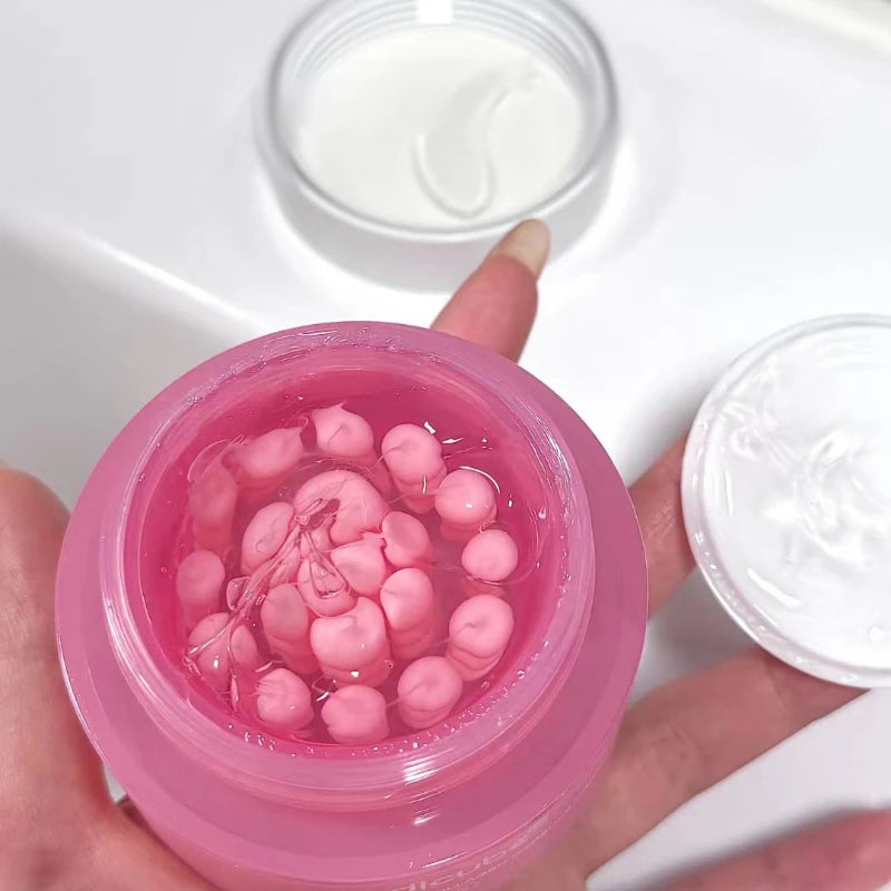 Open jar of Korean pink cream containing suspended pink collagen capsules in a clear, lightweight gel base.