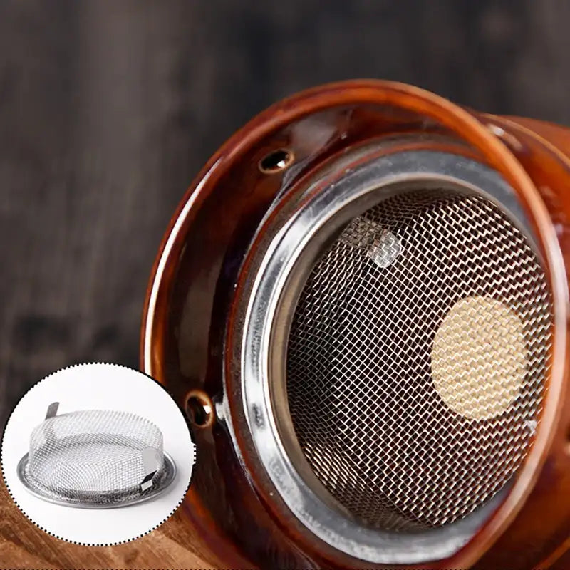 A brown ceramic moxibustion cup with a fine metal mesh filter inside, featuring a separate metal mesh insert inset.