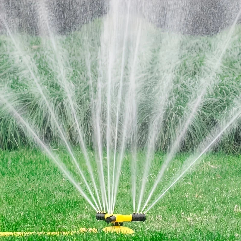 Wide fan water spray over grass from rotating sprinkler with yellow connector